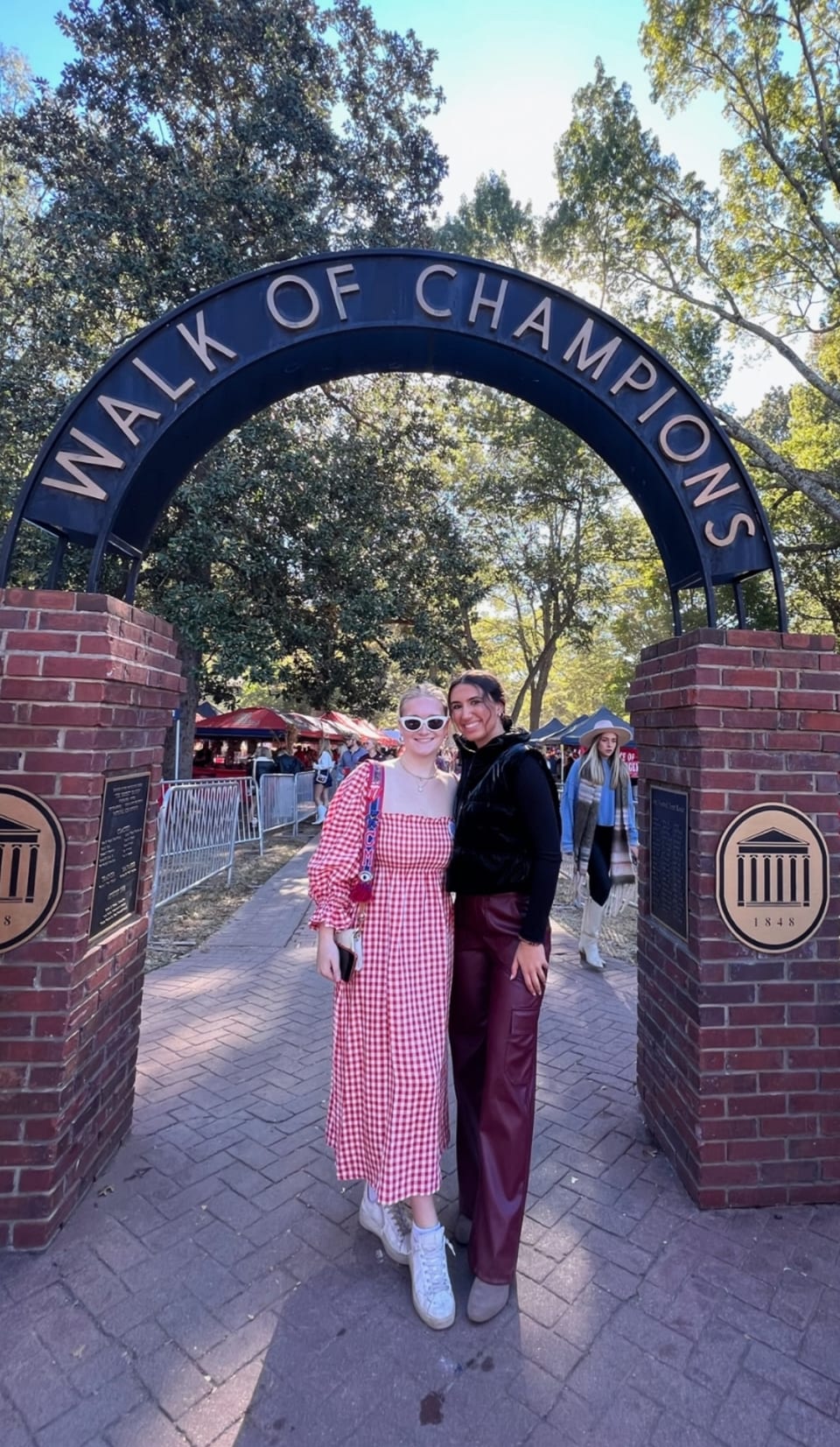 Carson with a friend beneath the Walk of Champions arch in the Grove at the University of Mississippi.